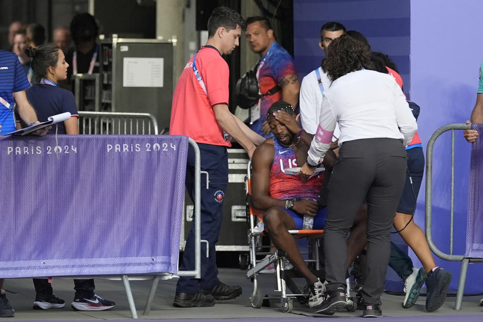 Noah Lyles, of the United States, is helped off the field after the men's 200 meters final at the 2024 Summer Olympics, Thursday, Aug. 8. 2024, Saint-Denis, France. (AP Photo/Matthias Schrader)