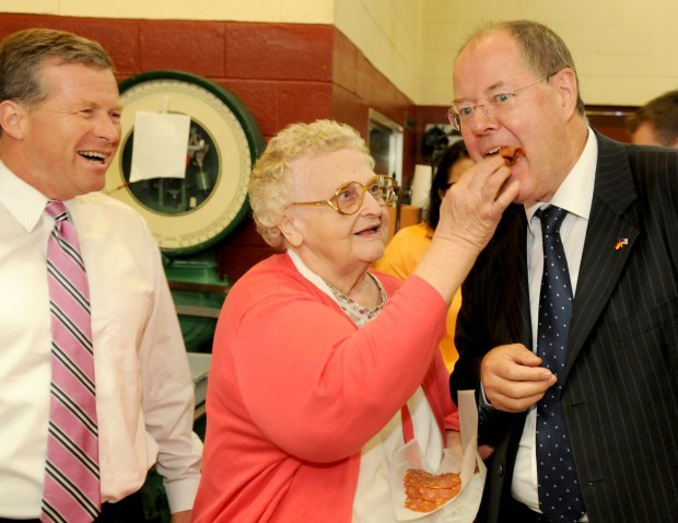 At Dietrich's Meats and Country Store in Krumsville, Verna Dietrich, the matriarch of the family, feeds Peer Steinbrueck a sample of the meat in 2014. Steinbrueck led a delegation of German officials visiting the Lehigh Valley and Berks County. On the left is Rep. Charles W. Dent.