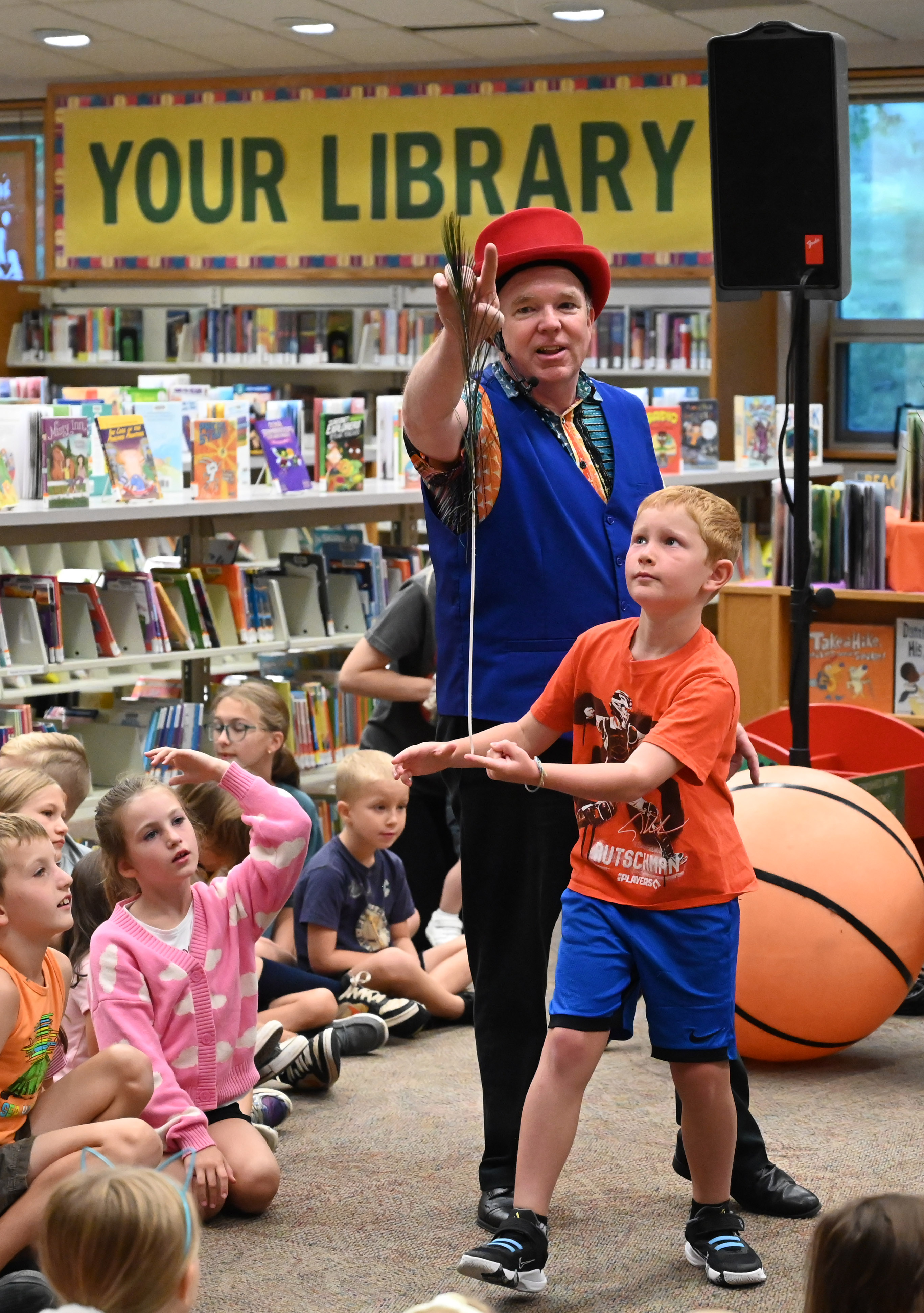 Gregory May watches as 8-year-old Manchester resident Aiden Walzl balances a peacock feather on his finger as part of his Circus Science act at the North Carroll Branch library on Thursday. May, a Columbia resident, combines science and circus tricks to educate and entertain her audiences through the background of a former Ringling Brothers circus performer Barnum and Bailey, a science teacher in Baltimore City and an instructor at Port Discovery. (Brian Krista/staff photo)