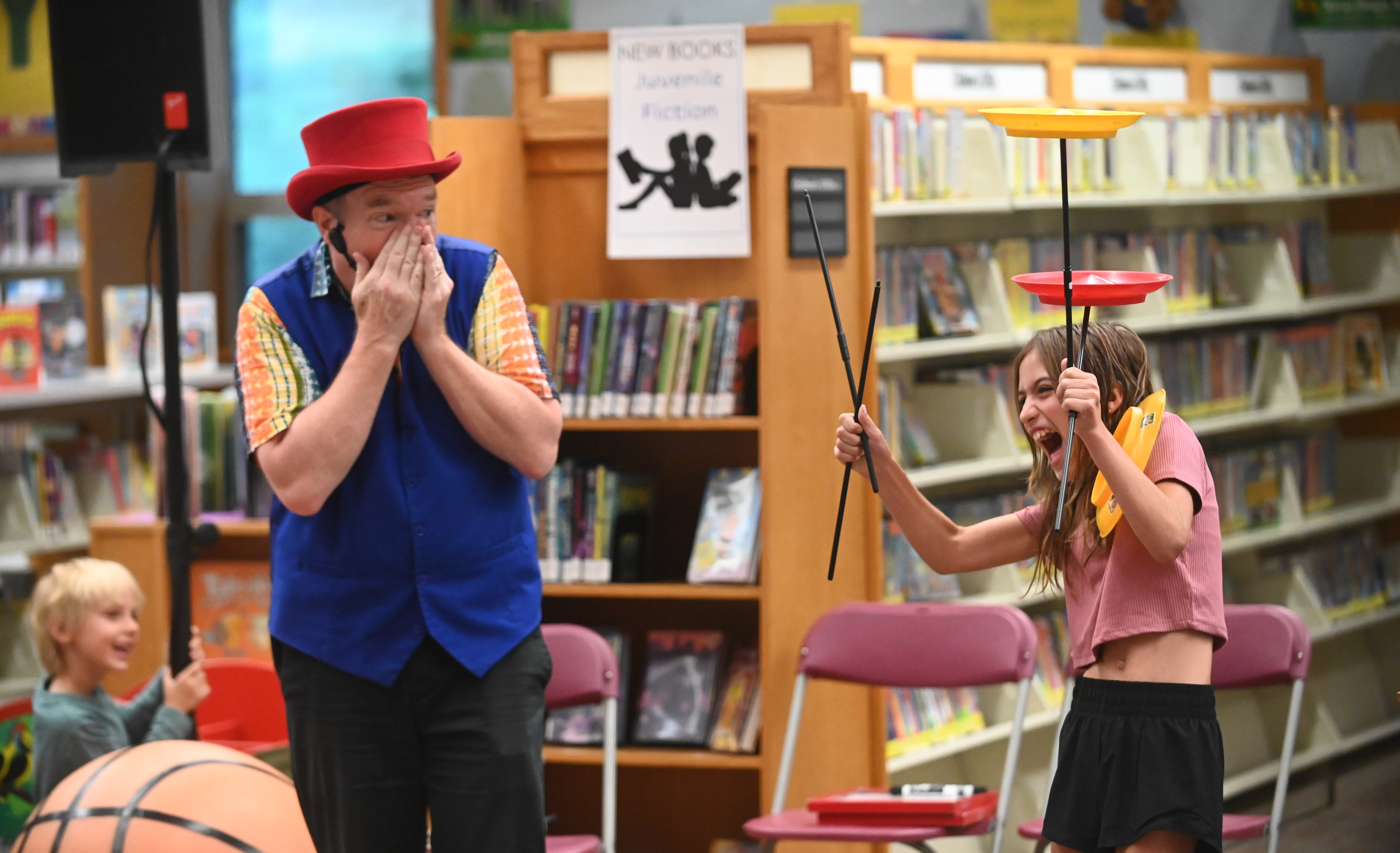 Gregory May reacts after jokingly knocking spinning plates out of the control of volunteer 9-year-old Tatum Westfall of Hampstead, as part of his Circus Science act at the North Carroll Branch library on Thursday. May, a Columbia resident, combines science and circus tricks to educate and entertain her audiences through the background of a former Ringling Brothers circus performer Barnum and Bailey, a science teacher in Baltimore City and an instructor at Port Discovery. (Brian Krista/staff photo)